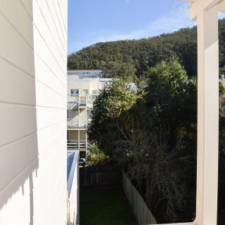 A sunny day view featuring buildings, trees, and a mountainous backdrop.