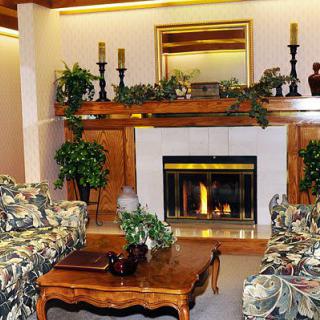 A cozy living room featuring a fireplace with decorative elements, including candles, a mirror, and greenery.