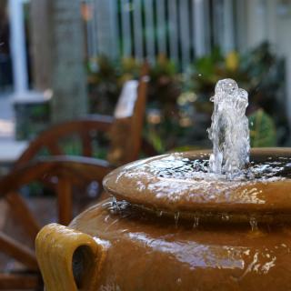 A small fountain built into a ceramic pot in a garden setting.