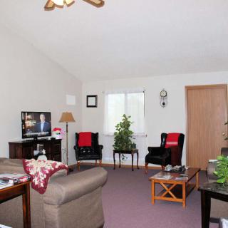 A cozy living room with seating area, television, and indoor plants.