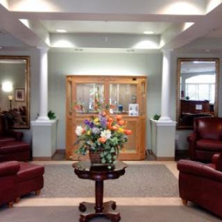A welcoming lobby area featuring comfortable seating, a floral arrangement, and decorative mirrors.