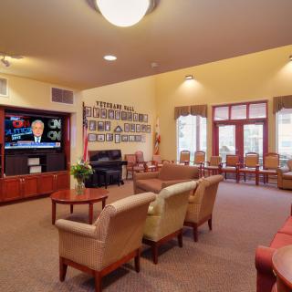 A cozy living room with comfortable seating, a television, and large windows.