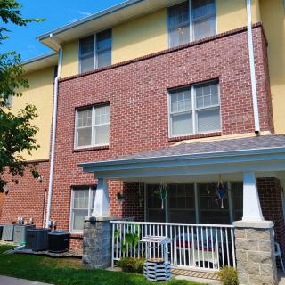 A three-story brick residential building with a front porch and multiple windows.