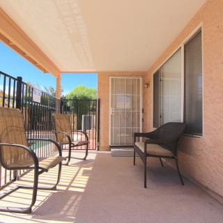 A sunny patio with outdoor seating, including chairs and a bench.