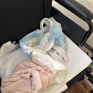 A wheelchair with a plastic bag and some clothes on it.