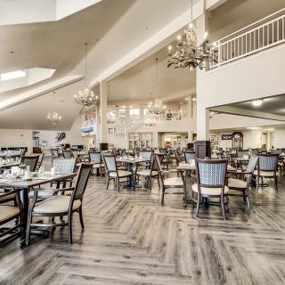A spacious and elegantly designed restaurant interior with neatly arranged tables and chandeliers.