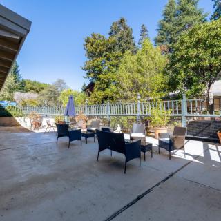 A sunny outdoor patio with comfortable seating and lush greenery.