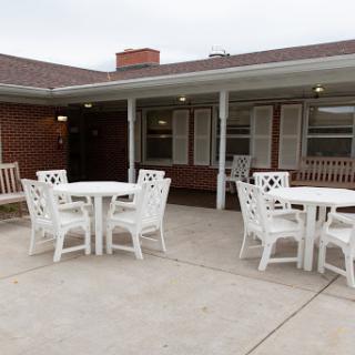 A serene outdoor seating area featuring white tables and chairs, perfect for social gatherings.