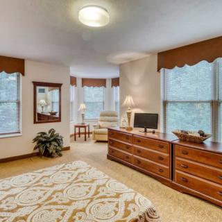 A cozy bedroom featuring a large dresser, an armchair by the window, and elegant decor.