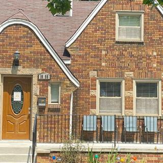 A brick residential house with a unique roof design and a front porch.