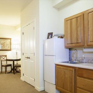 A cozy kitchen with wooden cabinets and a dining area in the background.