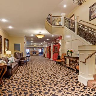 A spacious hotel lobby featuring elegant decor, with a staircase and comfortable seating arrangements.