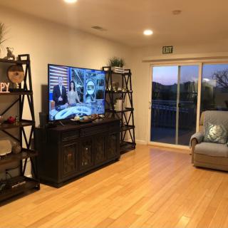 A cozy living room with a large television, bookshelves, and a sliding glass door leading outside.