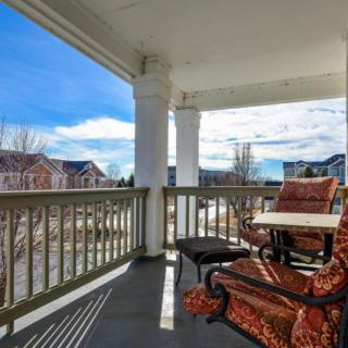 A cozy porch with comfortable seating overlooks a suburban neighborhood under a clear blue sky.