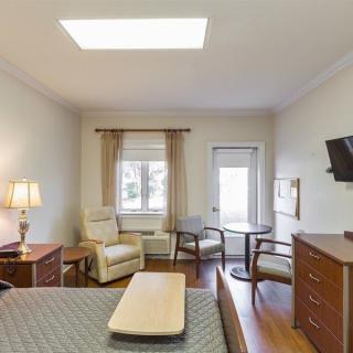 A cozy bedroom with a television, comfortable seating, and natural light from a window.