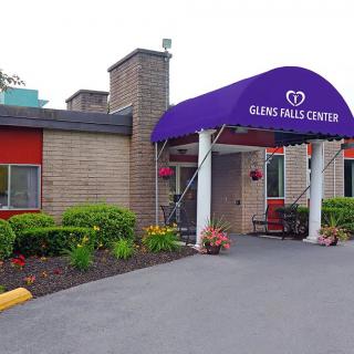 The entrance of a center with a purple awning and surrounding landscaping.