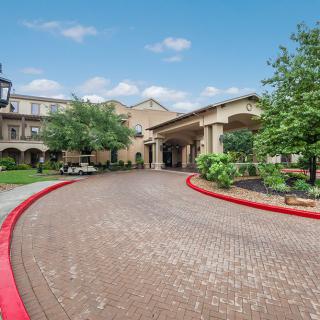 A hotel entrance with a circular driveway, surrounded by trees and landscaping.
