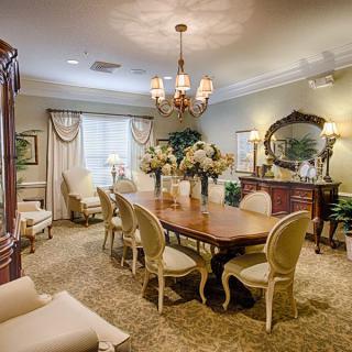 An elegantly decorated dining room with a traditional style, featuring a wooden table and chairs, a chandelier, and floral arrangements.