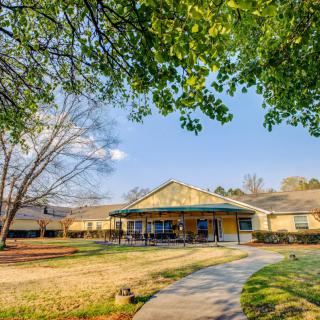 A sunny day view of a school building surrounded by trees and a grassy yard.