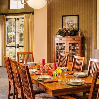 A cozy dining room with a wooden table set for dinner.