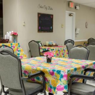 A brightly decorated dining area with tables covered in colorful floral tablecloths and chairs arranged around them.