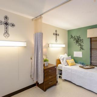 A serene bedroom featuring a comfortable bed, decorative crosses, and warm lighting.