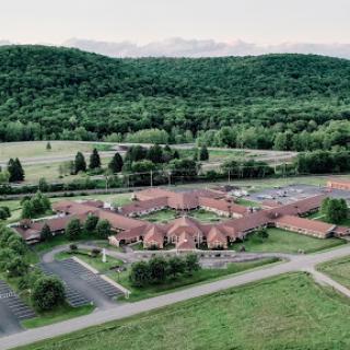 A serene aerial view showcasing the architectural layout of a building nestled among lush greenery and distant mountains.