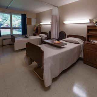 A hospital room with two beds, separated by a curtain, showcasing a simple and clean interior design.