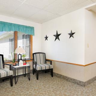 A cozy living room corner featuring striped chairs, a small table, and decorative star accents on the wall.