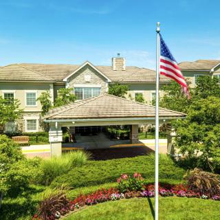 A well-maintained building with a U.S. flag, surrounded by lush greenery and gardens.