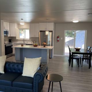 A modern open-concept living space featuring a comfortable sofa, dining table, and fully equipped kitchen.