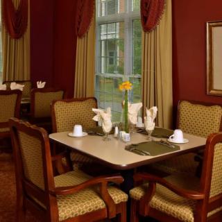 An elegantly set dining table in a formal restaurant with plush chairs and decorative curtains.