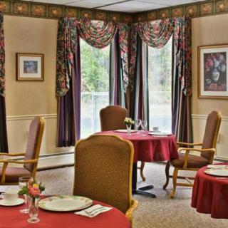 An elegantly decorated dining room with tables and chairs, adorned with patterned curtains and wall art.