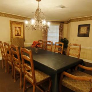A formal dining room with a large table, chairs, and an elegant chandelier.