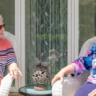 Two people sitting and chatting on a patio in a casual setting.