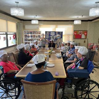 Residents of a care facility engaged in a group activity around a dining table.