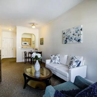 A modern living room with a white sofa, coffee table, and dining area in the background.