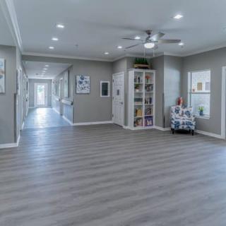 A spacious living area with modern wood flooring, large windows, and a ceiling fan provides a comfortable and stylish space.
