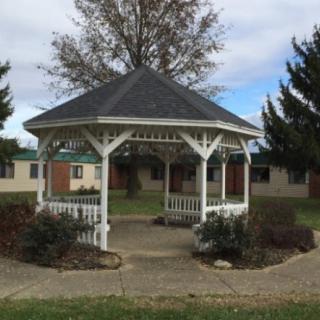 A white gazebo surrounded by greenery and situated in a park setting.