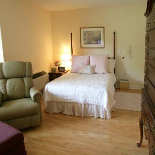 A cozy bedroom featuring a bed with white bedding, complemented by comfortable seating and warm lighting.