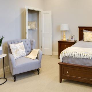 A cozy bedroom with a comfortable armchair and well-made bed.