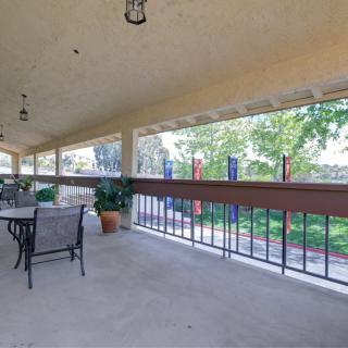 A spacious covered patio with outdoor seating and a view of the garden.