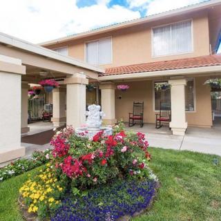 A two-story house with a well-maintained garden featuring colorful flowers.