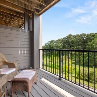 A cozy balcony with outdoor seating overlooking a lush green landscape.