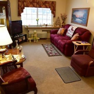 A cozy living room with a maroon sofa, armchair, and a small television.