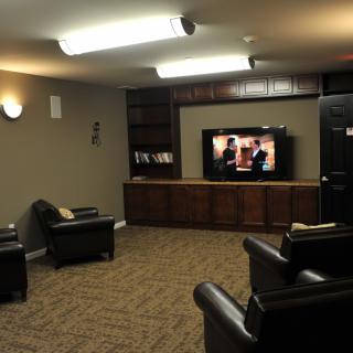 A cozy living room with leather seating arranged around a television, creating a home theater atmosphere.