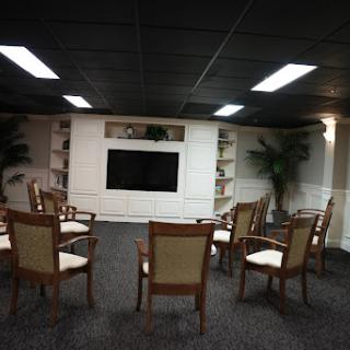 A cozy meeting room featuring arranged seating, a television, and decorative plants.