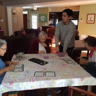 Residents enjoying a bingo game at a community center with the assistance of a caregiver.