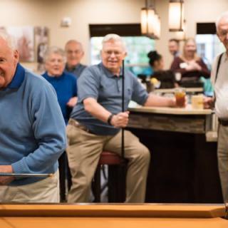 A group of elderly men enjoying a game of billiards in a social setting.