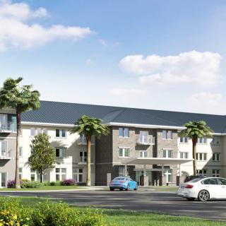 A modern residential building with palm trees and parked cars under a partly cloudy sky.